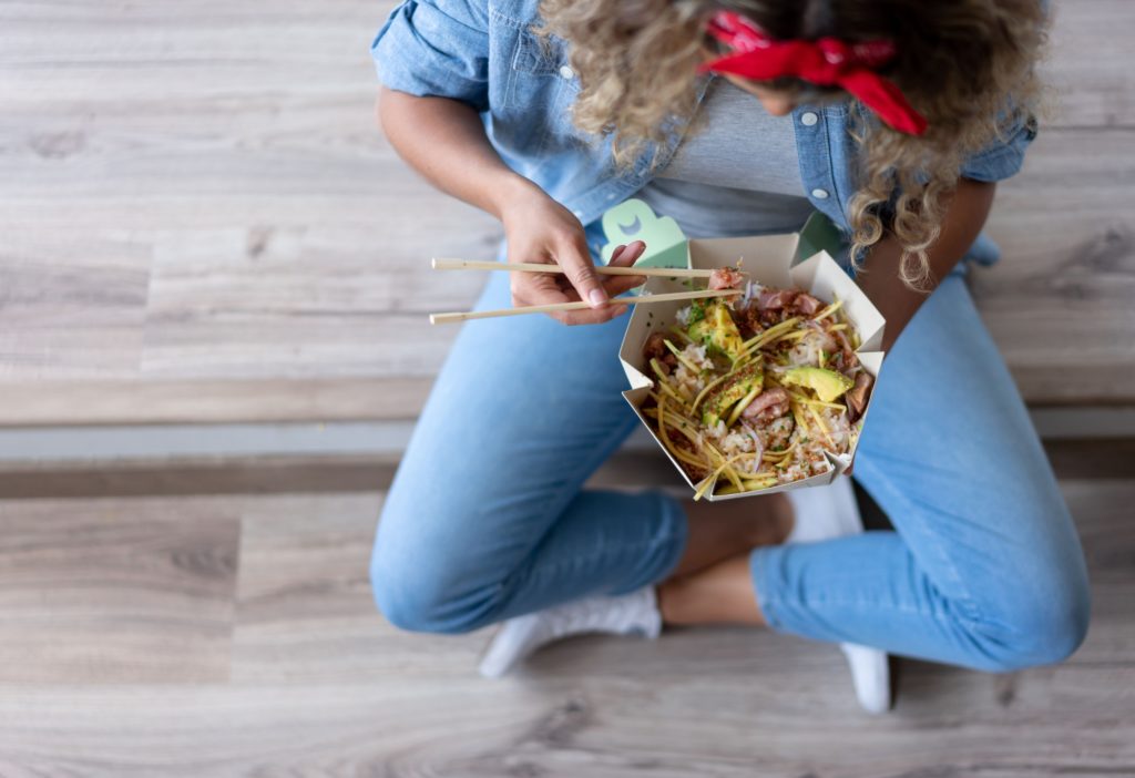Close-up on a woman eating a poke bowl at home while moving house