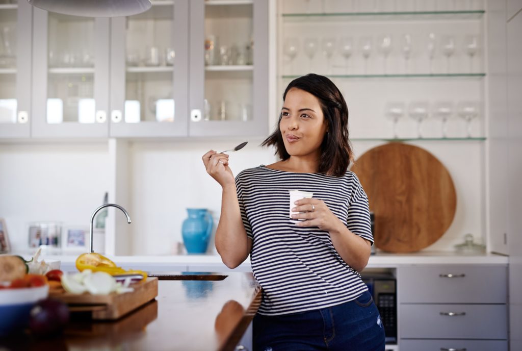 Shot of an attractive young woman eating yogurt at home